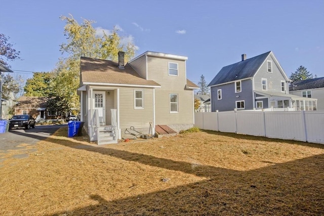 rear view of property featuring a chimney and entry steps