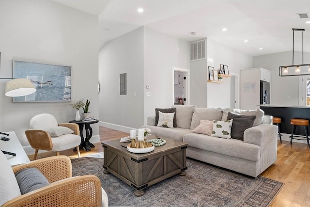 living room featuring vaulted ceiling, electric panel, and hardwood / wood-style floors