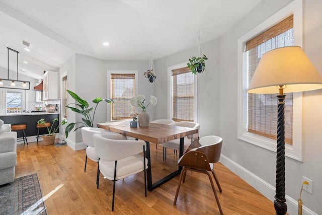 dining area with vaulted ceiling and light wood-type flooring