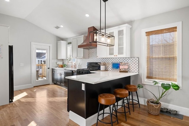 kitchen featuring white cabinets, custom range hood, hanging light fixtures, and black appliances