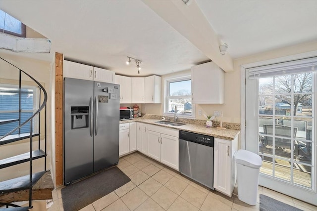 kitchen featuring appliances with stainless steel finishes, white cabinetry, a sink, and light tile patterned flooring