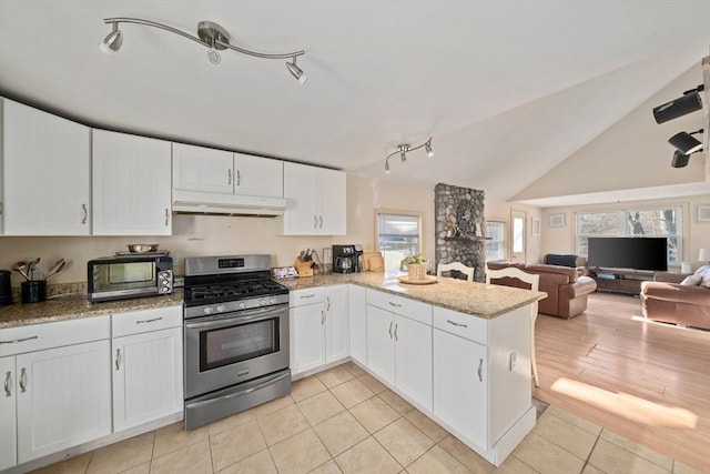 kitchen featuring stainless steel range with gas cooktop, lofted ceiling, white cabinets, a peninsula, and under cabinet range hood