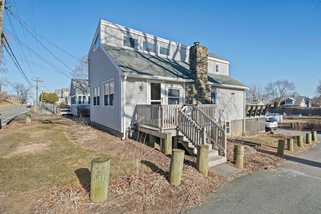 view of front of house with a shingled roof and a chimney