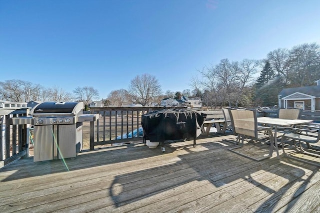 wooden terrace featuring outdoor dining space and grilling area