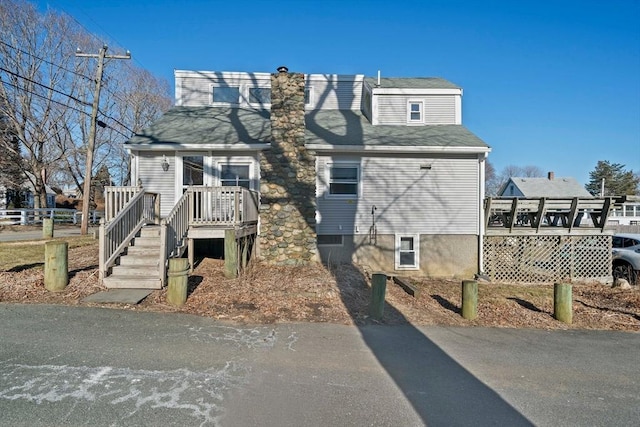 view of front of property featuring roof with shingles and a deck