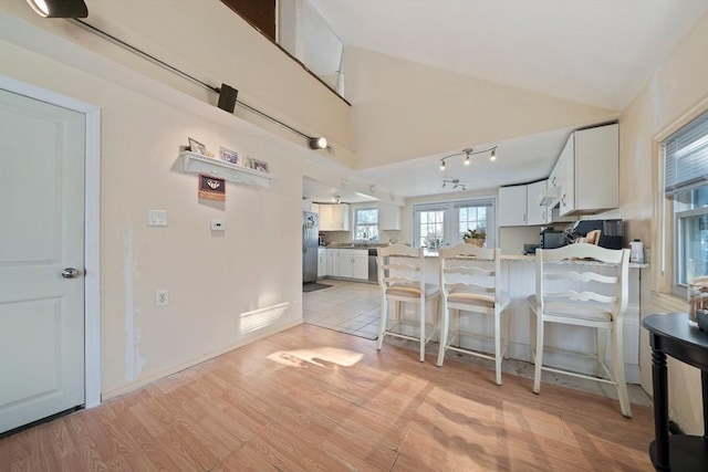 kitchen with light wood-type flooring, freestanding refrigerator, white cabinetry, and a peninsula