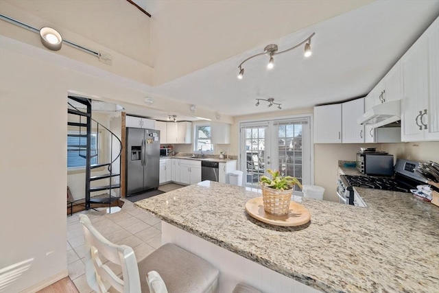 kitchen with under cabinet range hood, a peninsula, white cabinets, french doors, and appliances with stainless steel finishes