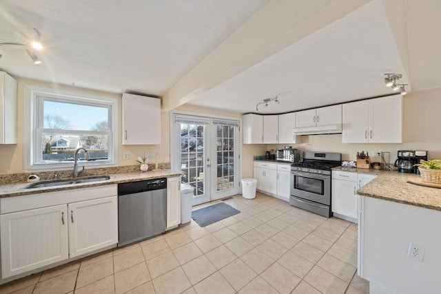 kitchen featuring stainless steel appliances, french doors, under cabinet range hood, white cabinetry, and a sink