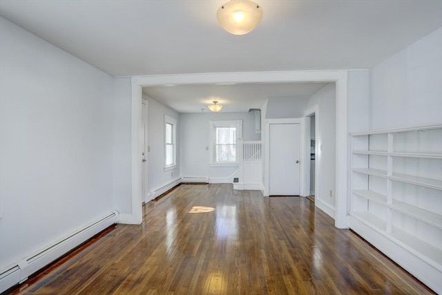 unfurnished room featuring baseboard heating and dark hardwood / wood-style flooring