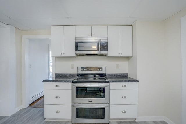 kitchen with a paneled ceiling, white cabinetry, appliances with stainless steel finishes, and a baseboard heating unit