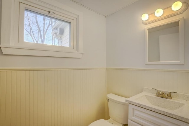 bathroom featuring vanity, wood walls, and toilet