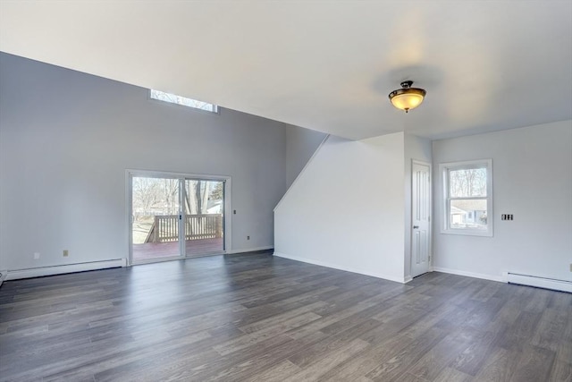 unfurnished living room featuring plenty of natural light, baseboard heating, and dark wood-type flooring