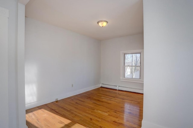 unfurnished room featuring wood-type flooring and a baseboard radiator