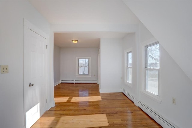 bonus room featuring a healthy amount of sunlight, light hardwood / wood-style flooring, and a baseboard radiator