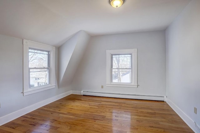 additional living space featuring light wood-type flooring, baseboard heating, and vaulted ceiling