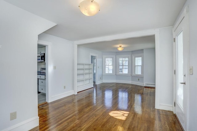 unfurnished living room featuring dark hardwood / wood-style floors and a baseboard radiator