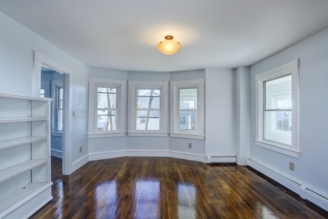 empty room with dark hardwood / wood-style flooring and a baseboard heating unit