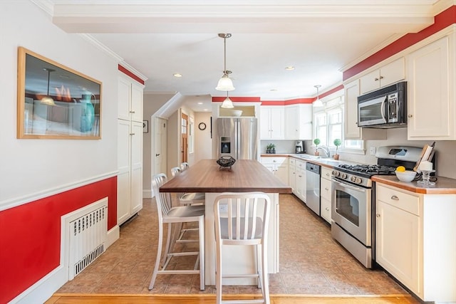kitchen with white cabinets, stainless steel appliances, butcher block countertops, and a kitchen bar