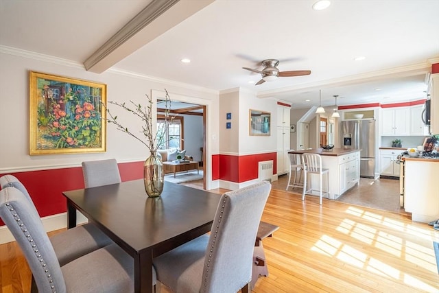dining area with crown molding, baseboards, ceiling fan, and light wood-style flooring