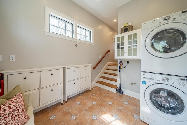 laundry area featuring cabinet space, light tile patterned flooring, stacked washer / drying machine, recessed lighting, and baseboards