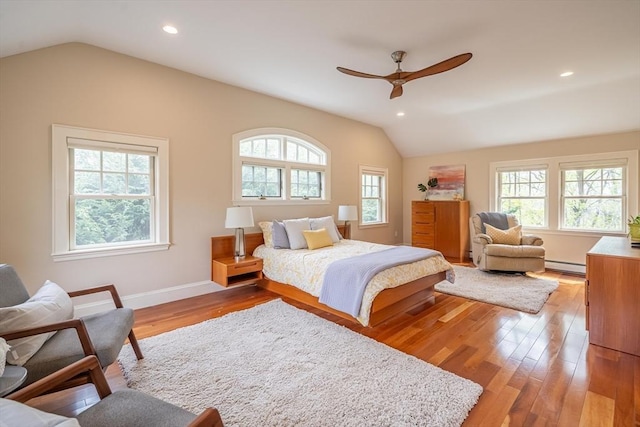 bedroom with baseboards, baseboard heating, recessed lighting, light wood-style flooring, and vaulted ceiling
