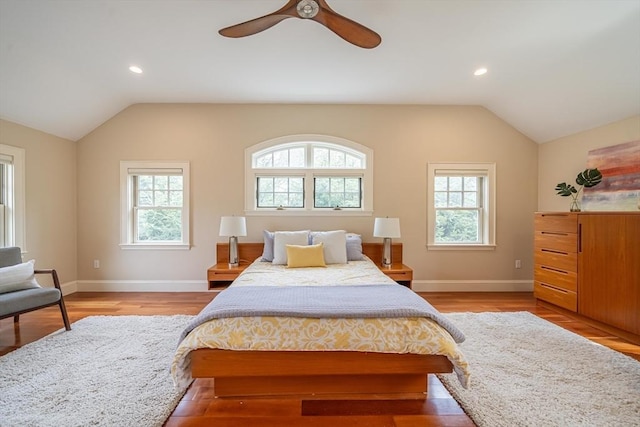 bedroom with baseboards, vaulted ceiling, multiple windows, and light wood-type flooring