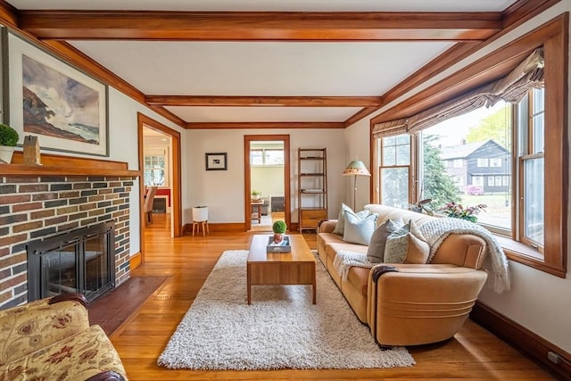 living room with crown molding, a fireplace, light wood-style floors, baseboards, and beamed ceiling