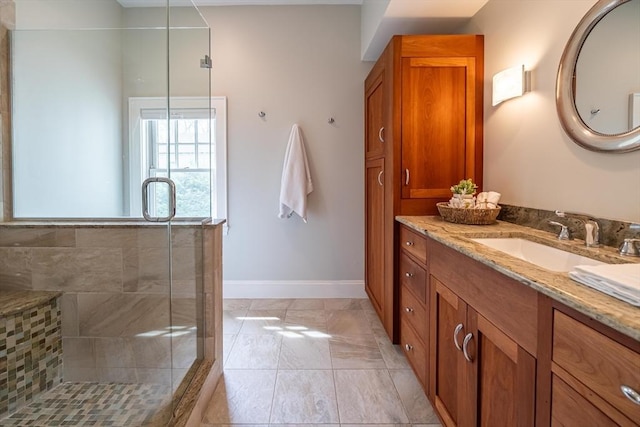 bathroom with vanity, marble finish floor, baseboards, and a tile shower