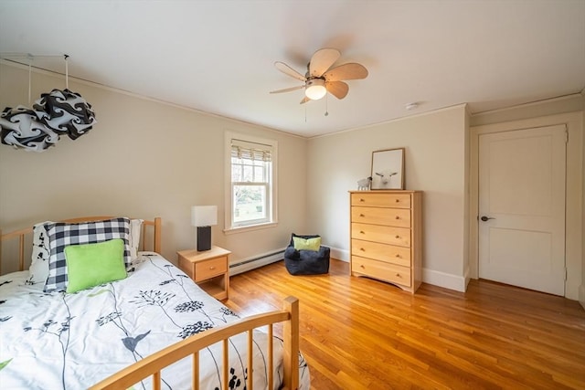 bedroom with ornamental molding, baseboards, ceiling fan, light wood-type flooring, and a baseboard heating unit