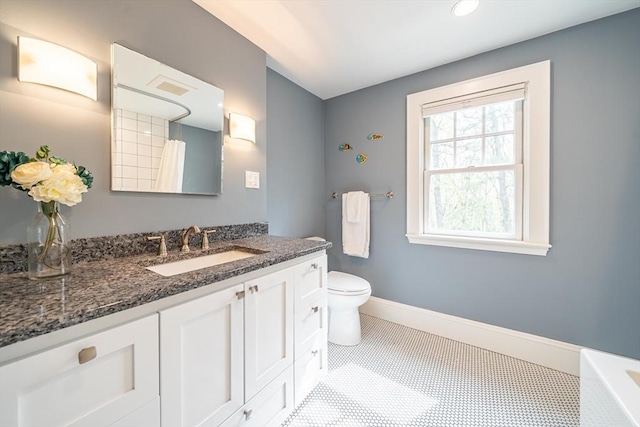 bathroom featuring a tub, vanity, baseboards, and toilet