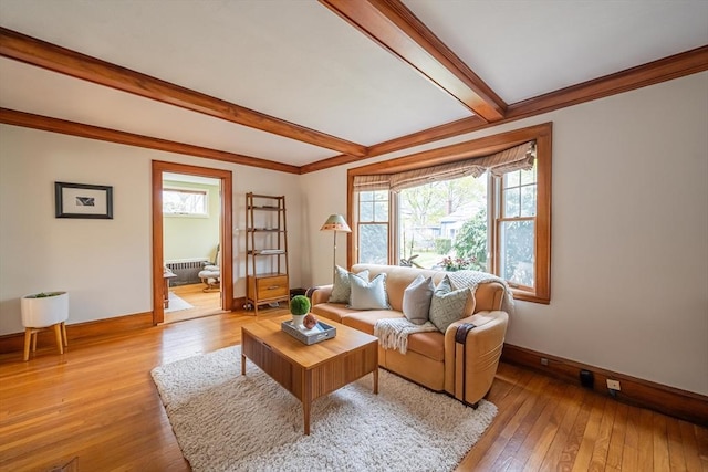 living area with radiator heating unit, baseboards, light wood finished floors, and beam ceiling