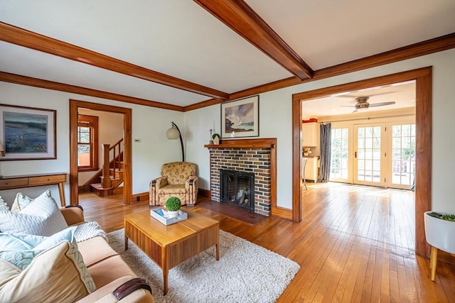 living room featuring light wood-style flooring, a wealth of natural light, stairway, and beamed ceiling