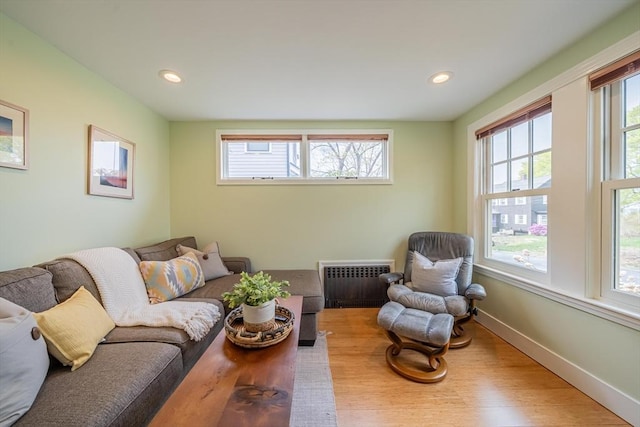living area featuring recessed lighting, a wealth of natural light, radiator heating unit, and wood finished floors