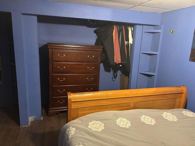 bedroom featuring a drop ceiling and dark wood-type flooring