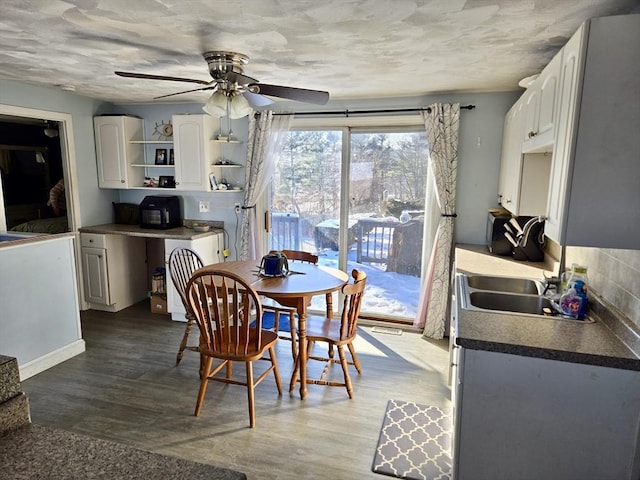 dining space with sink, wood-type flooring, and ceiling fan