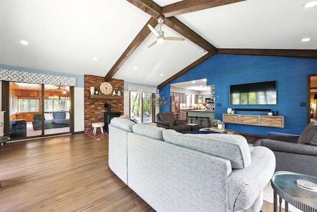living room featuring a wood stove, wood finished floors, and a ceiling fan