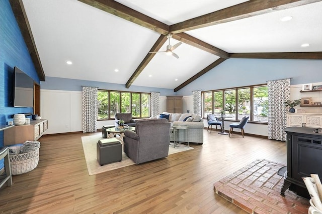 living room featuring wood finished floors, ceiling fan, a wood stove, and baseboards