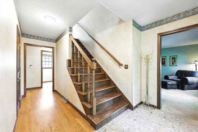 stairs featuring baseboards, a textured ceiling, and wood finished floors