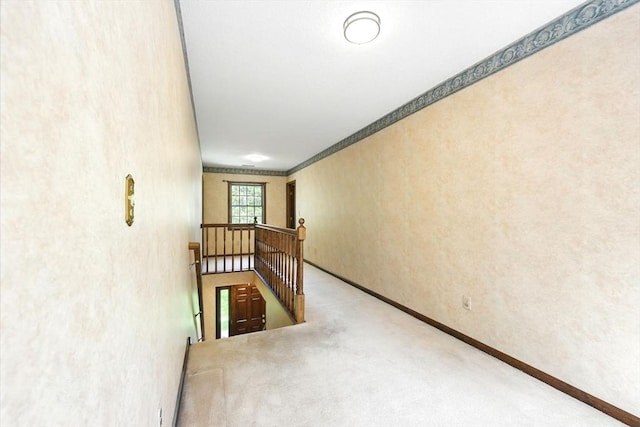 hallway with an upstairs landing, baseboards, carpet flooring, and crown molding