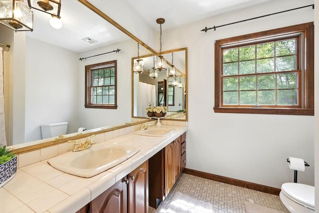 bathroom with toilet, baseboards, double vanity, and curtained shower