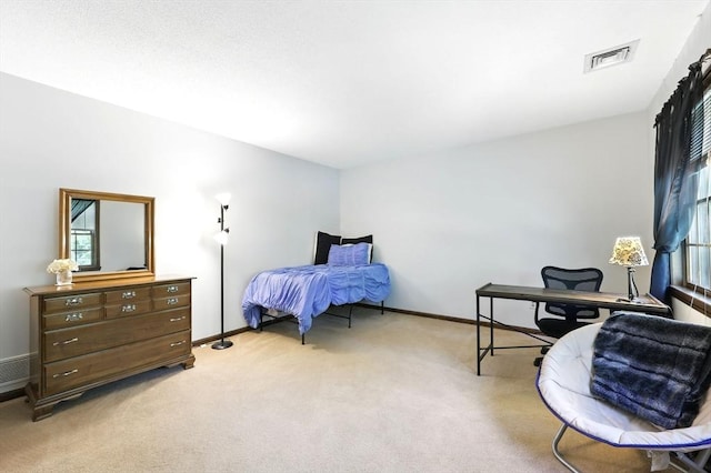 bedroom with light colored carpet, a desk, and baseboards