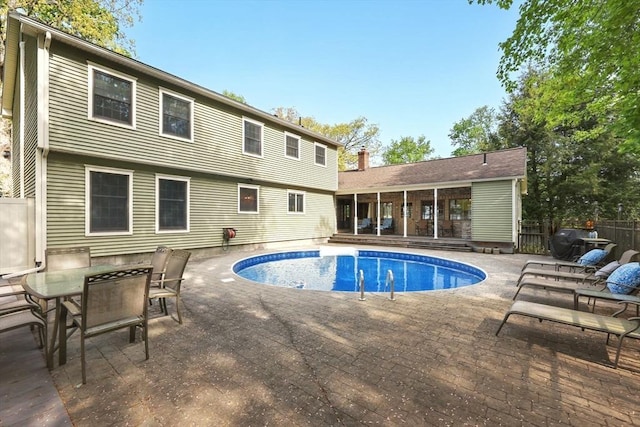 view of pool featuring a sunroom, a patio, fence, and outdoor dining space