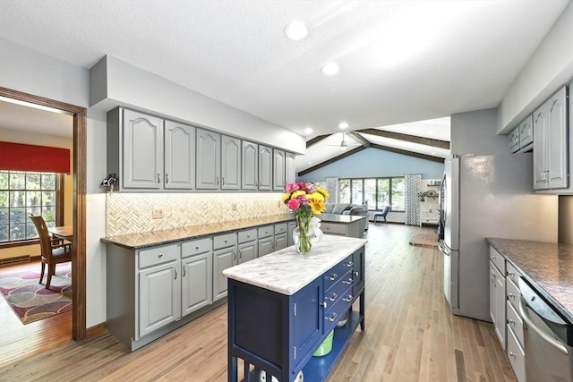 kitchen with gray cabinets, light wood finished floors, decorative backsplash, vaulted ceiling, and open floor plan
