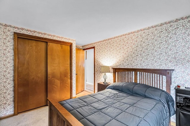 bedroom featuring wallpapered walls, light colored carpet, a closet, and baseboards