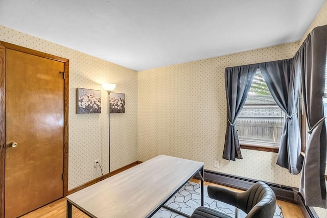 office with light wood-style floors and wallpapered walls