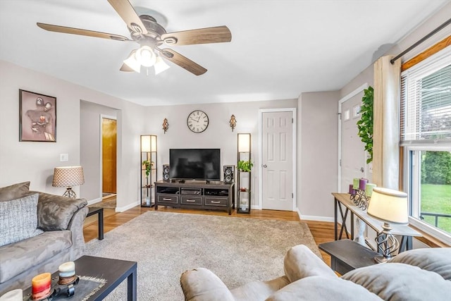 living room featuring a ceiling fan, baseboards, and wood finished floors