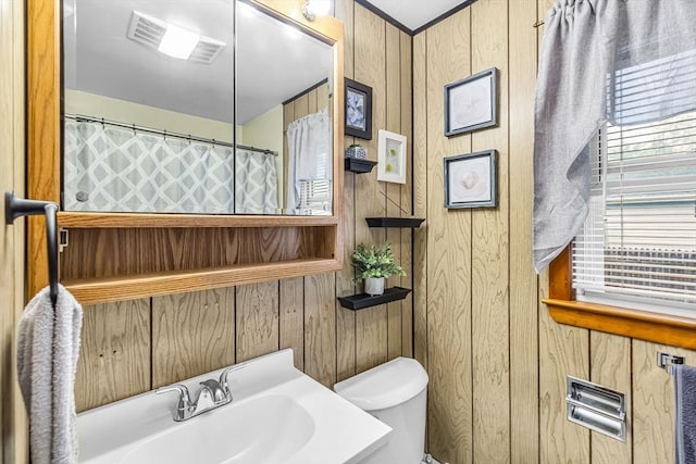 full bath featuring wood walls, toilet, a sink, and a shower with curtain