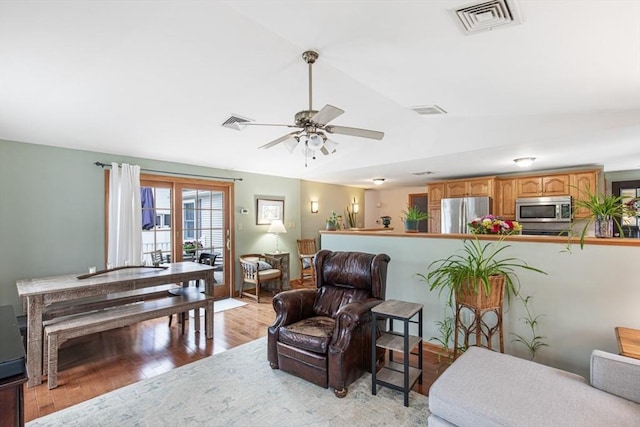 living room featuring lofted ceiling, ceiling fan, and light wood-type flooring