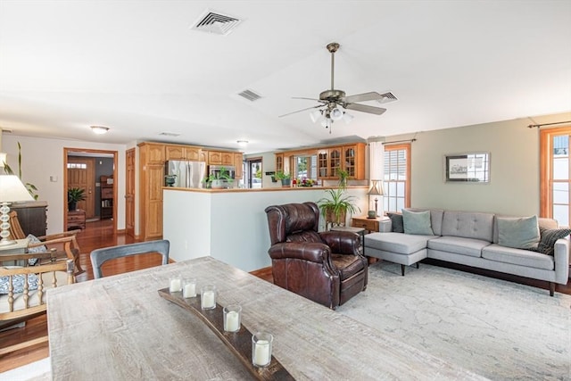 living room featuring healthy amount of natural light, a ceiling fan, vaulted ceiling, and light wood-style flooring