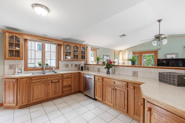 kitchen featuring dishwasher, a sink, backsplash, light countertops, and vaulted ceiling
